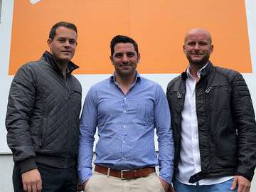 Foto von links: Dominik Kagerer, Tobias Löwe und Sebastian Czaplicki. (Im Hintergrund das orangene Banner befindet sich auf der Hauswand des IGZ.)